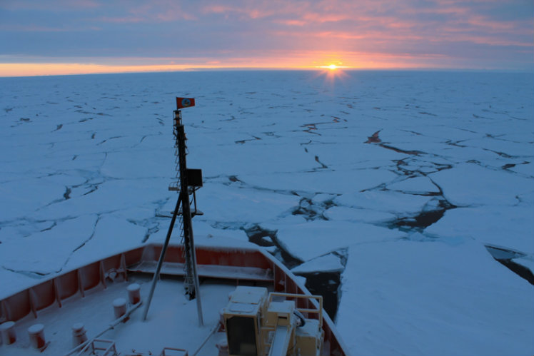 A sun sets on the icy sea.